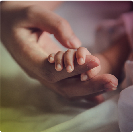 Photo of a baby's hand grabbing the index finger of an adult hand
