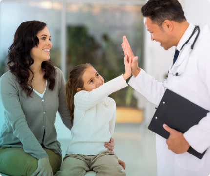 A doctor giving a high-five to a child sitting next to an adult woman