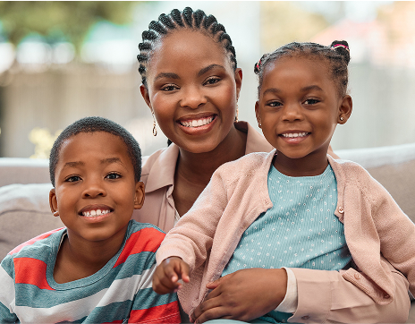 Photo of a woman smiling with a male child sitting to her left and a female child sitting on her lap to the right.